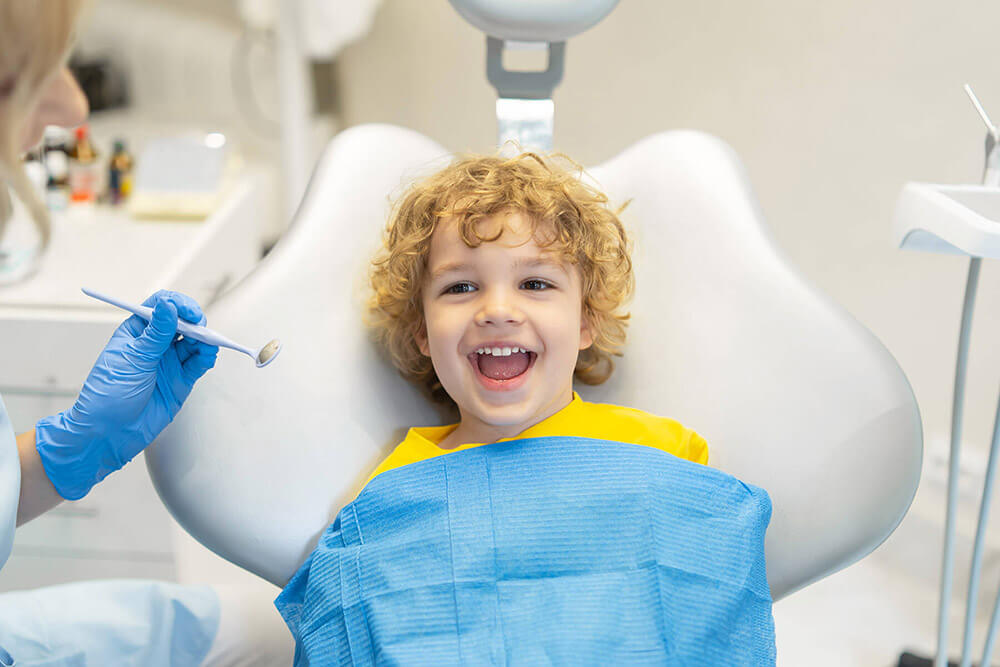 young child smiling in the chair at the dentist