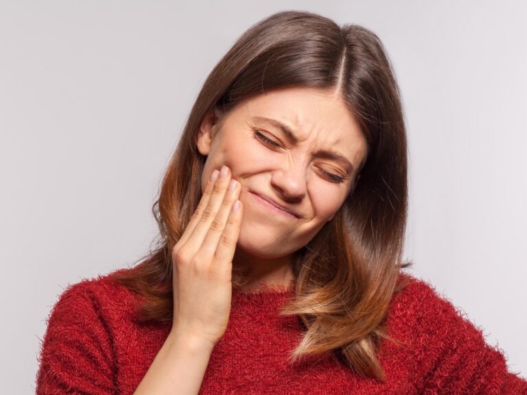 Woman holding her cheek in pain due to a dental emergency or severe toothache at Winter Dental.