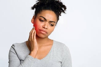 A woman touches her jaw with a pained expression, highlighting red inflammation from a suspected tooth infection or jaw discomfort.